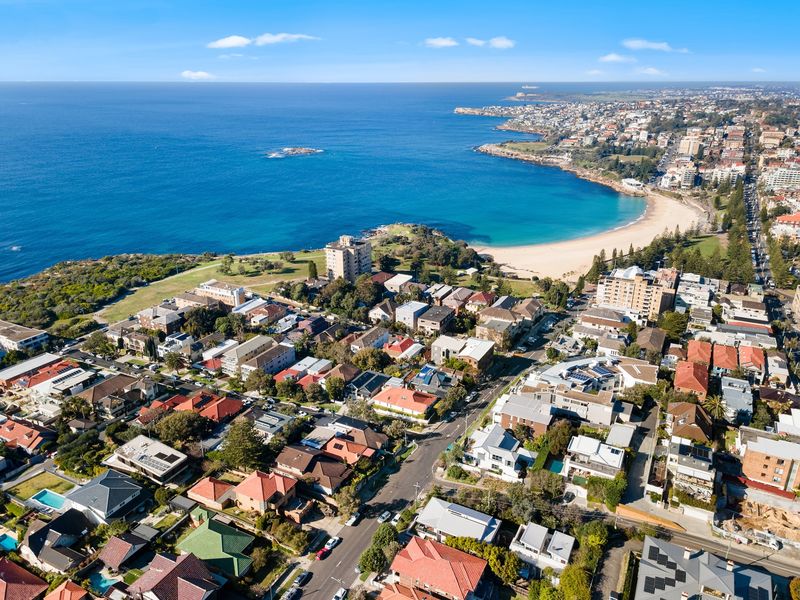 Aerial view of a beachside suburb and a curved sandy beach